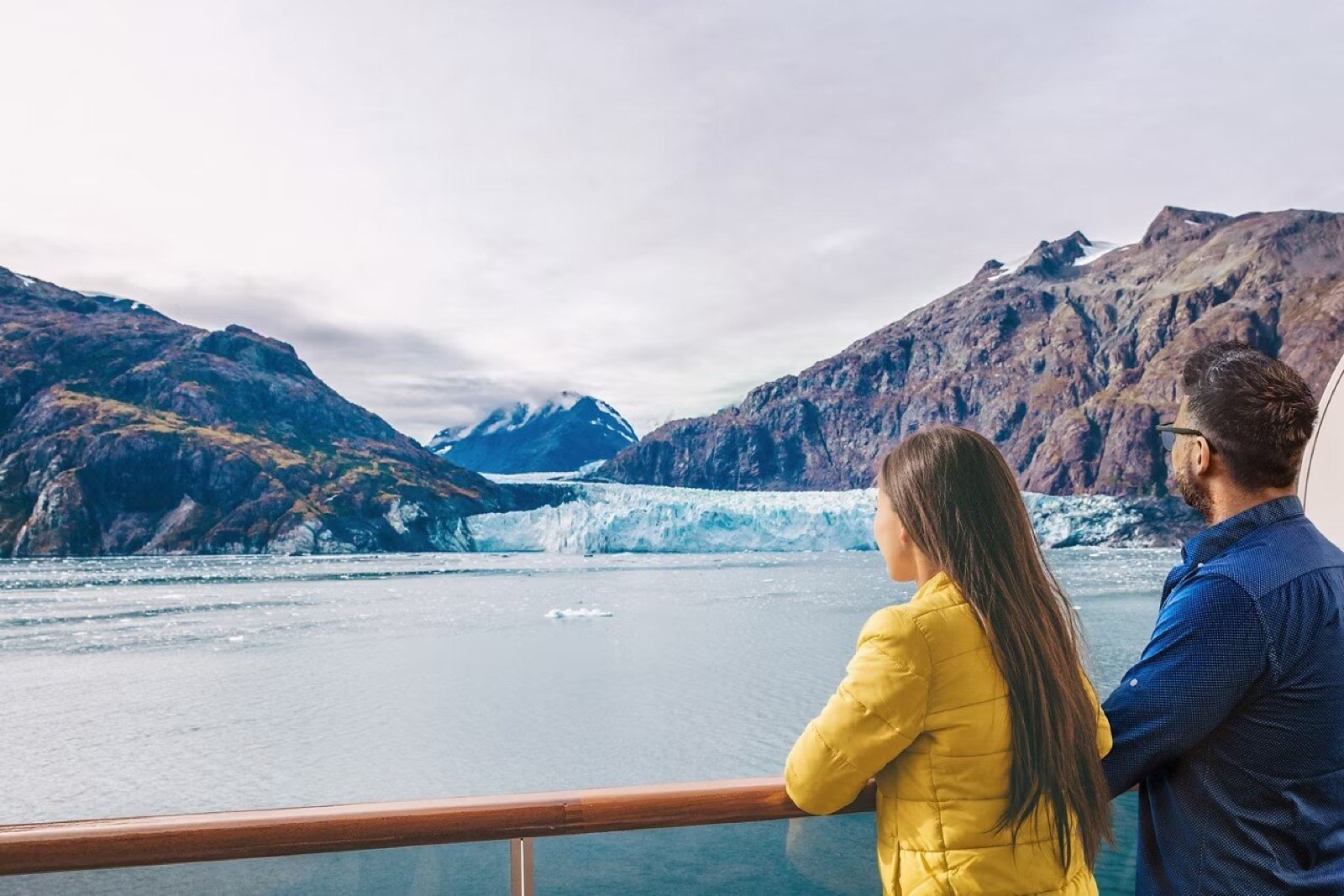 A couple watching an Alaskan glacier from the deck of a cruise ship